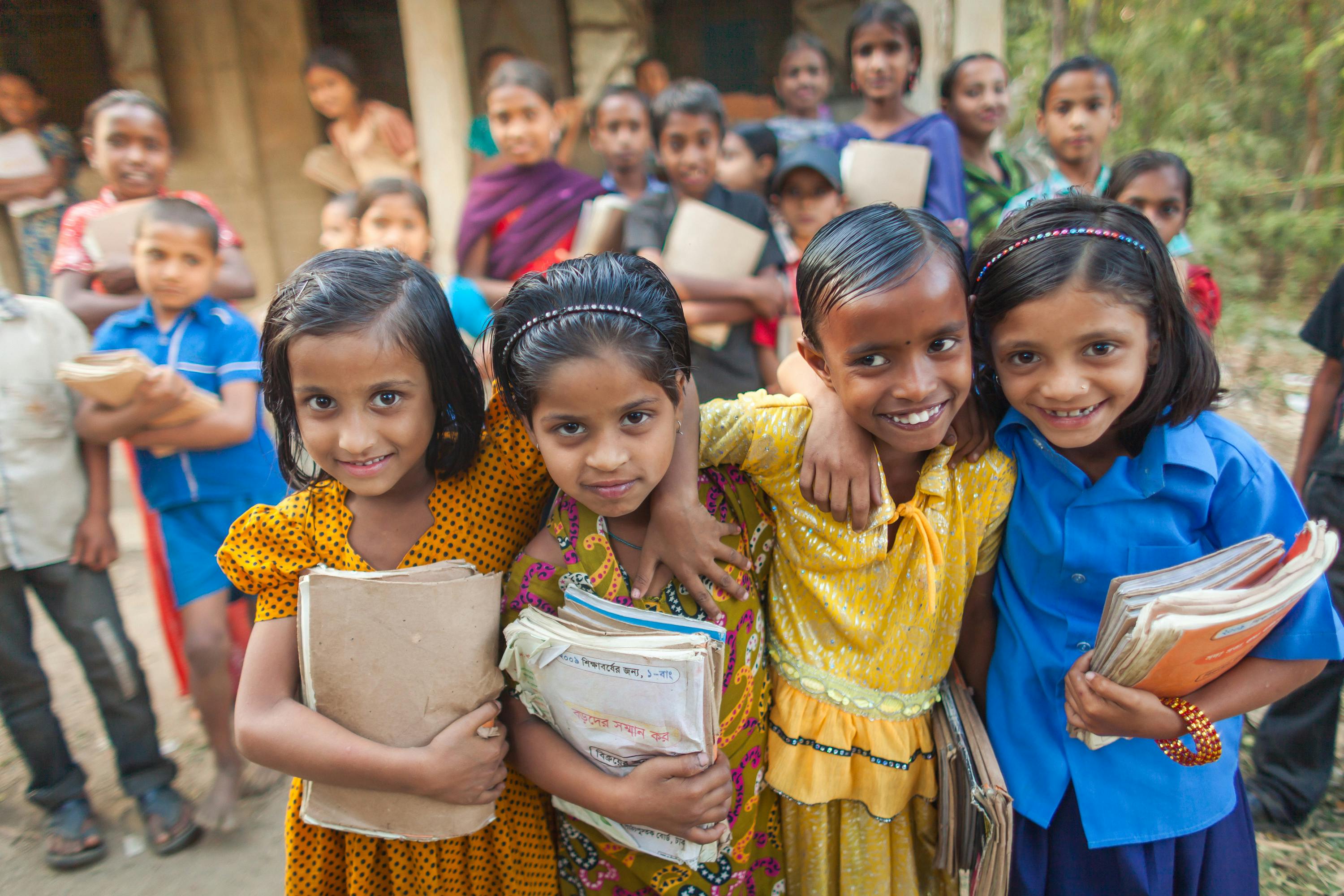 Smiling rural school children holding their textbooks and notebooks outside their school